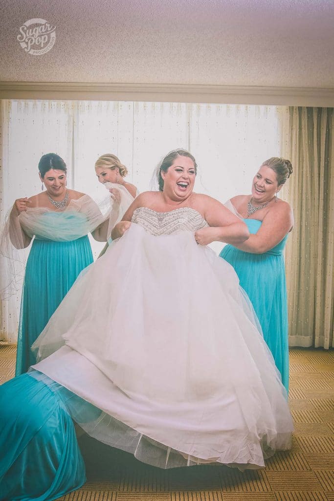 Sugar Pop Productions - bridesmaids helping bride into dress