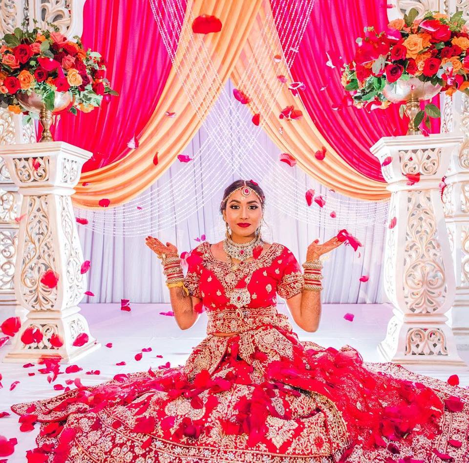 That First Moment - Hindi bride in stunning red dress tossing flower petals