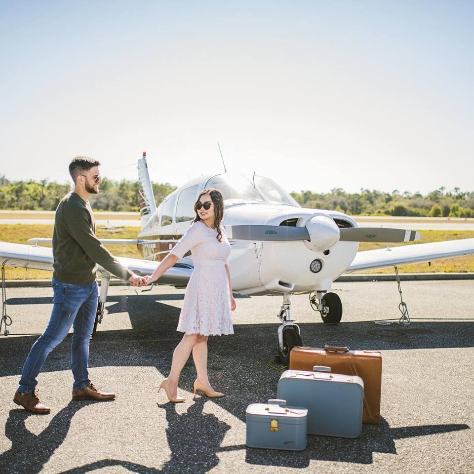 That First Moment - newlyweds with suitcases in front of small plane