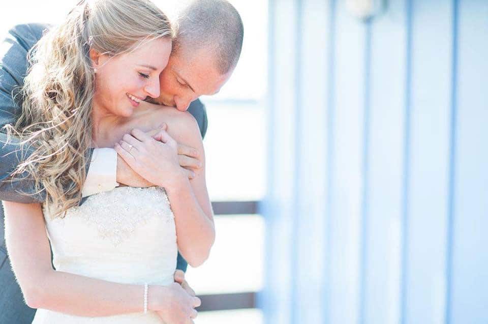 That First Moment - groom kissing bride's shoulder