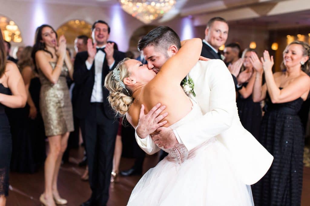 iRock Your Party, on the dance floor a groom dips his bride for a kiss while guests cheer