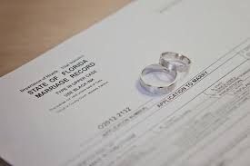 two silver rings sitting on marriage license