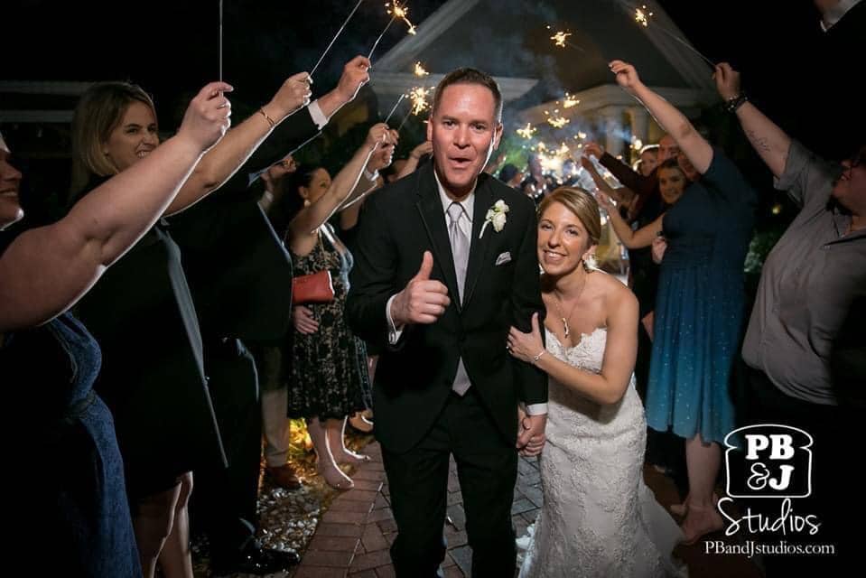 bride and groom giving thumbs up as they walk through wedding guests holding sparklers