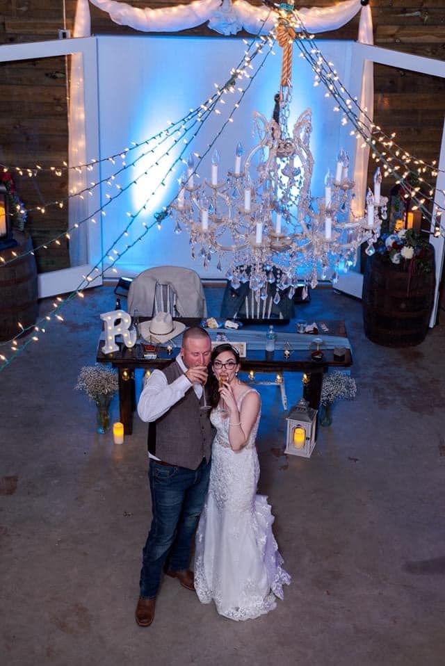 bride and groom standing under large chandelier at wedding receptions