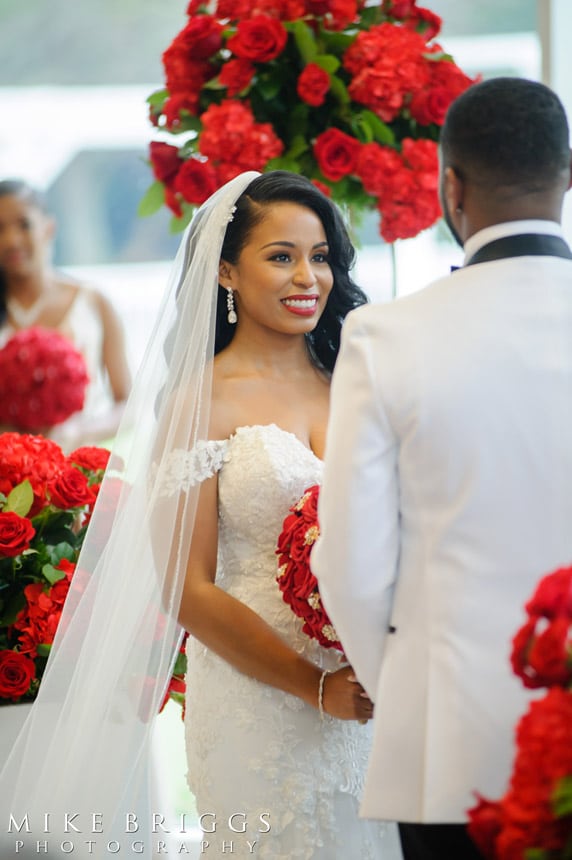 Bride with red flowers gazing at groom
