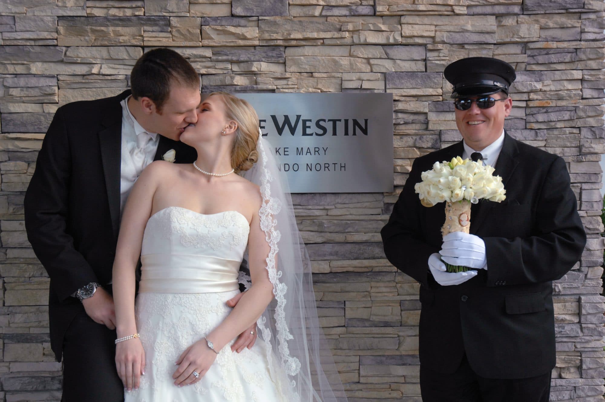 Chris Gillyard Photography - bride and groom kiss while doorman holds bouquet