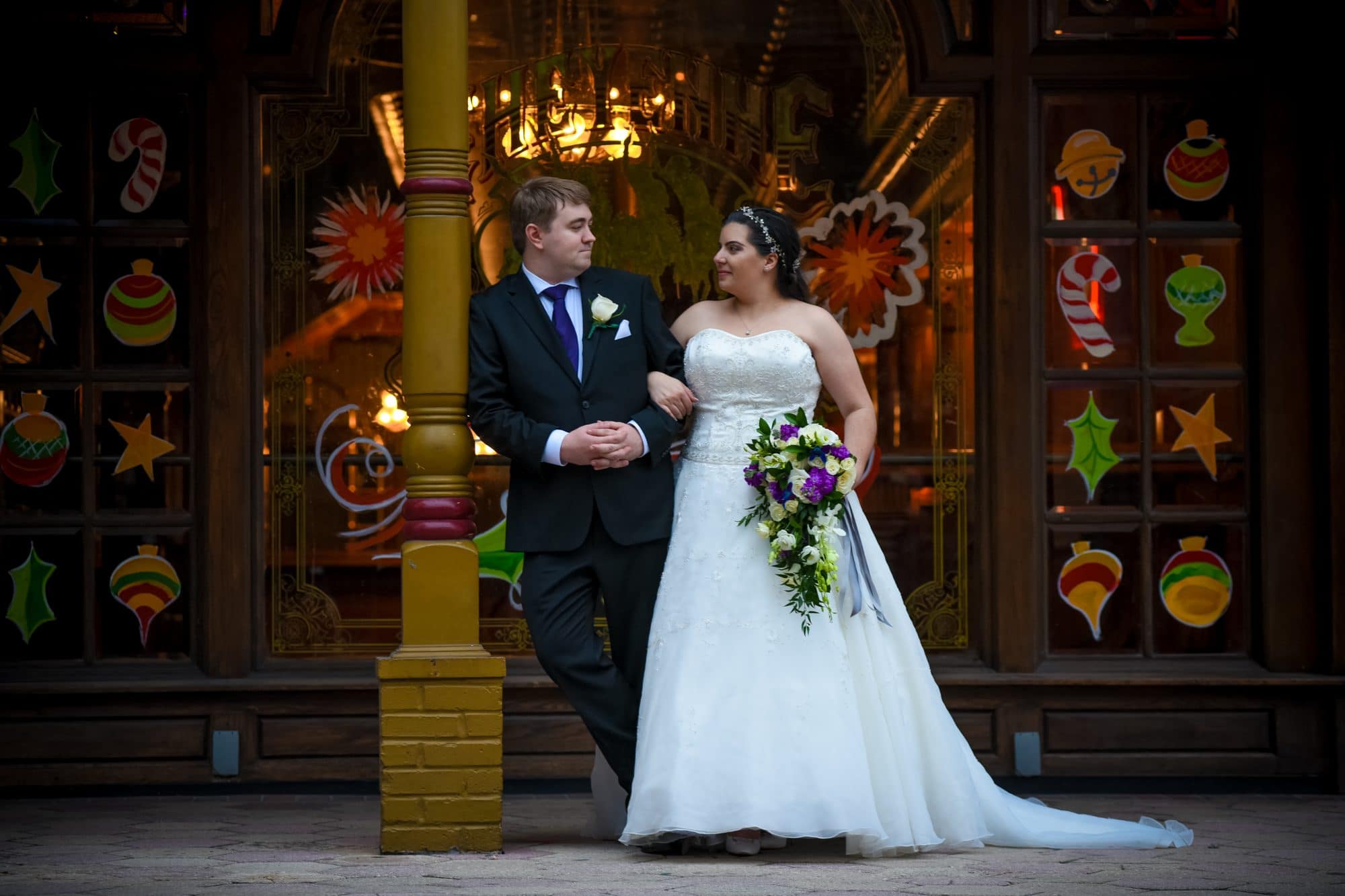 Chris Gillyard Photography - bride and groom in front of storefront with windows painted for Christmas