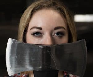 Epic-Axe-Throwing-Woman holding axe in front of face so only eyes are showing