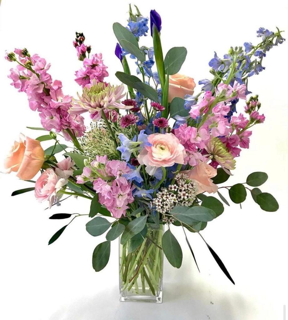 spring bouquet in clear vase with blue, pink, and orange flowers
