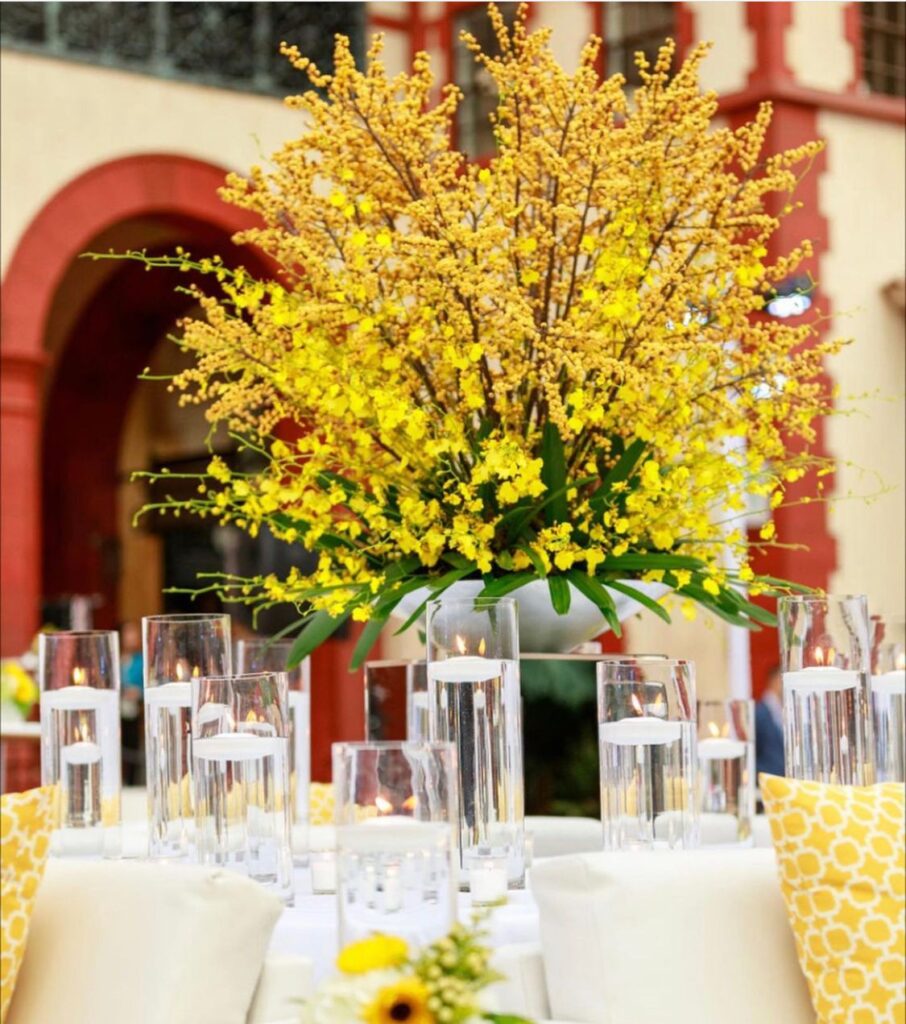 large yellow floral arrangement on white table at wedding reception by Fairbanks Florist