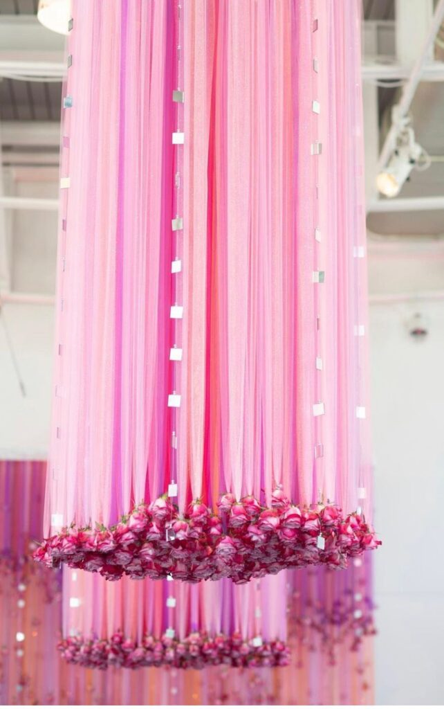 long pink curtains hanging from ceiling with pink flowers hanging from the bottom