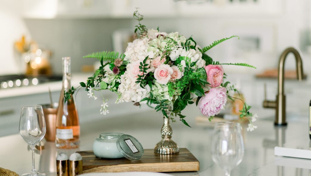 small pink and green bouquet in gold vase on kitchen counter