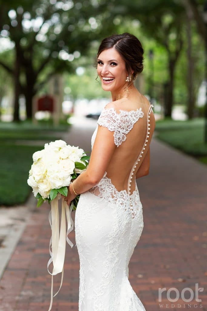 Bride posing outside with white bouquet and white ribbons by Fairbanks Florist