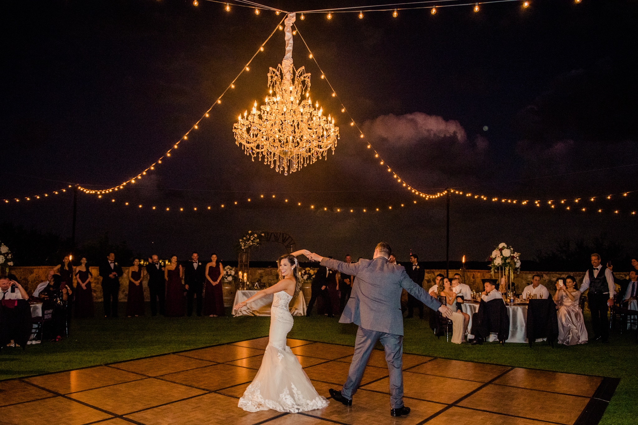 Bride & groom dancing under the lights and chandelier 