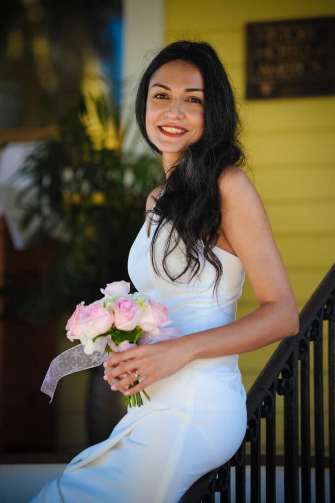 bride leaning on handrail in front of yellow building while holding pink flowers - chris gillyard orlando wedding photography