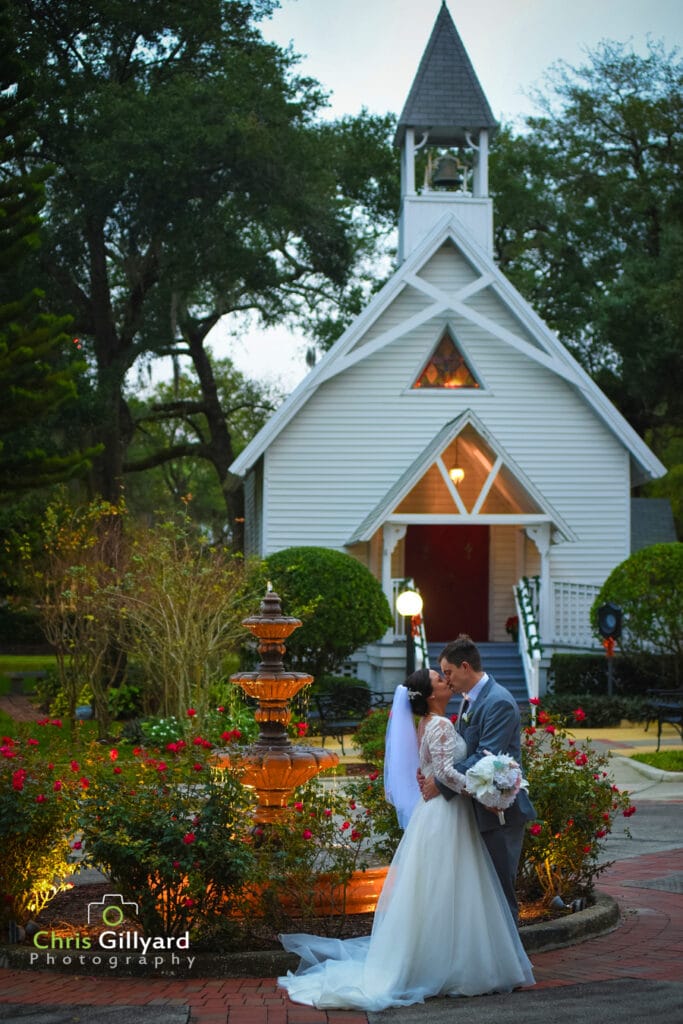 bride and groom kissing in front of small white chapel with fountain and gardens - chris gillyard orlando wedding photography