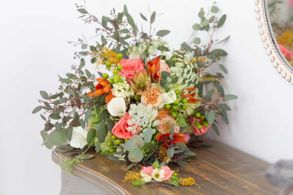 flowers in cream, orange and peach on a wooden table from The Flower Studio