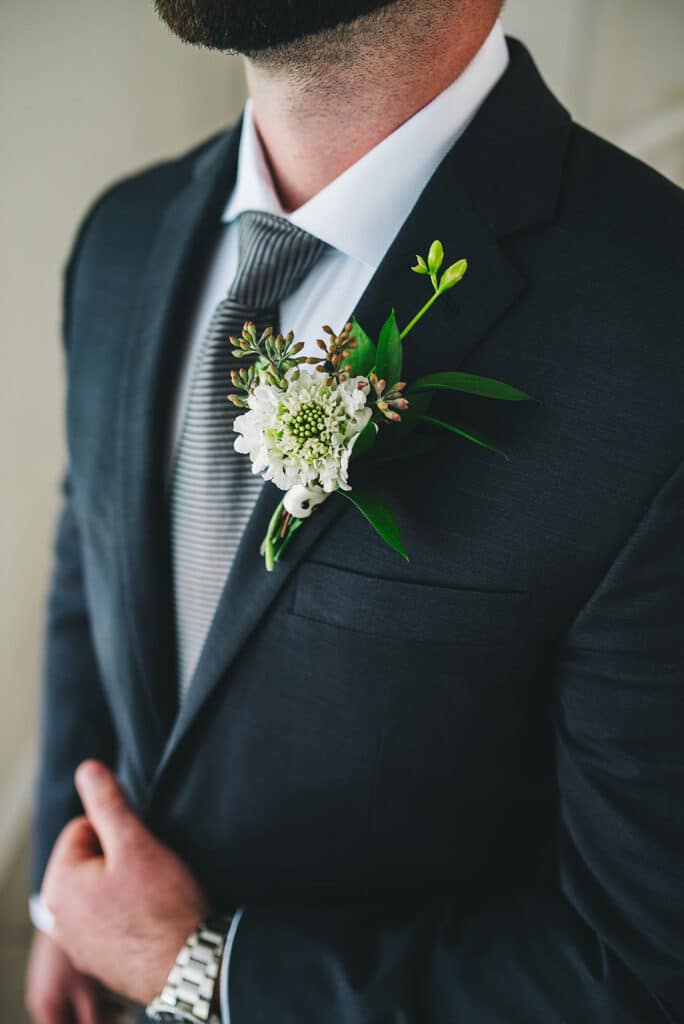 groom wearing a boutonniere prepared by The Flower Studio