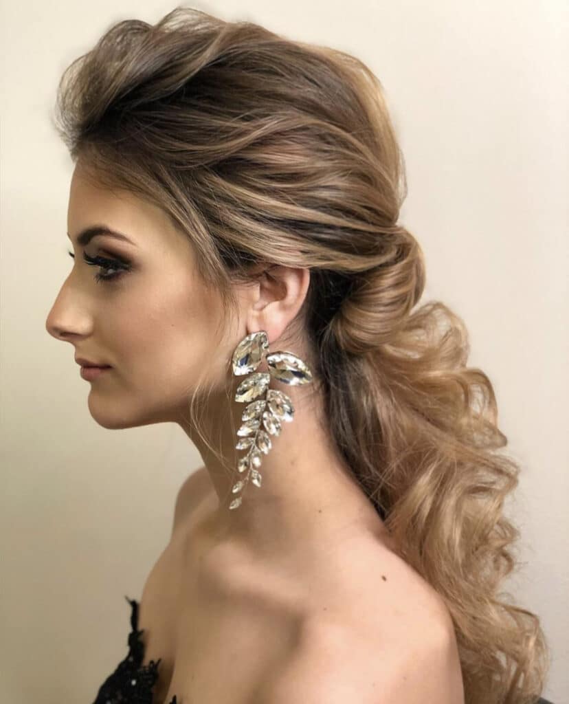 bride facing side with large silver earrings and braided hair