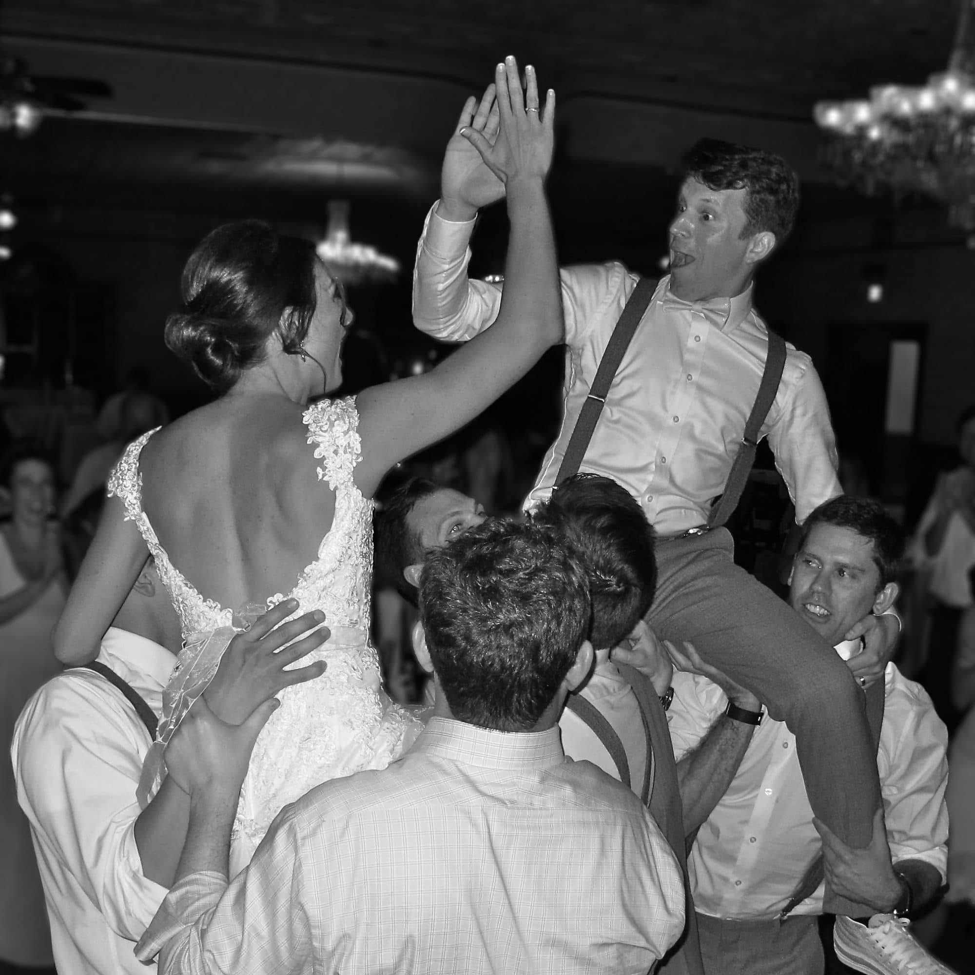 Classic-Disc-Jockeys-Bride and Groom giving high five while being lifted up by groomsmen at reception