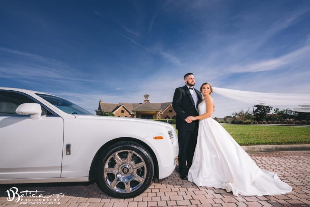 Exotic-Limo-Orlando-Bride and Groom stnading outside next to a white Rolls Royce Ghost