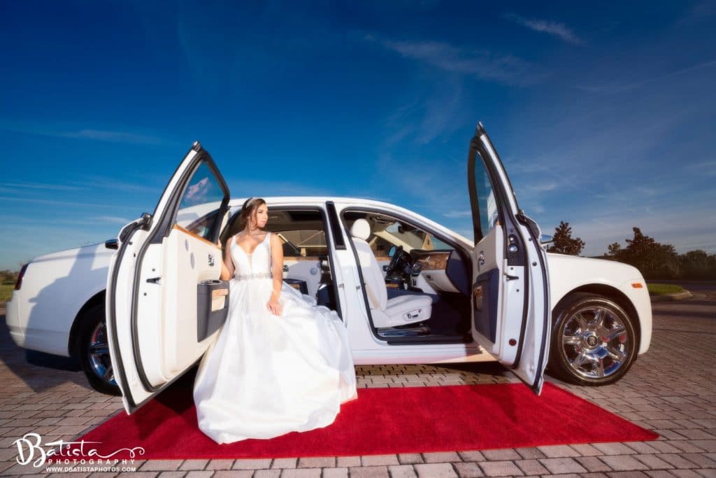 Exotic-Limo-Orlando-Bride getting out of a white Rolls Royce Ghost with red carpet