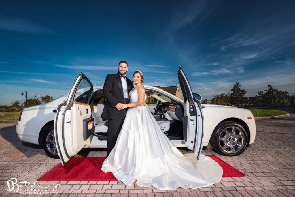 Exotic-Limo-Orlando-Bride and Groom standing on red carpet in front of white Rolls Royce Ghost