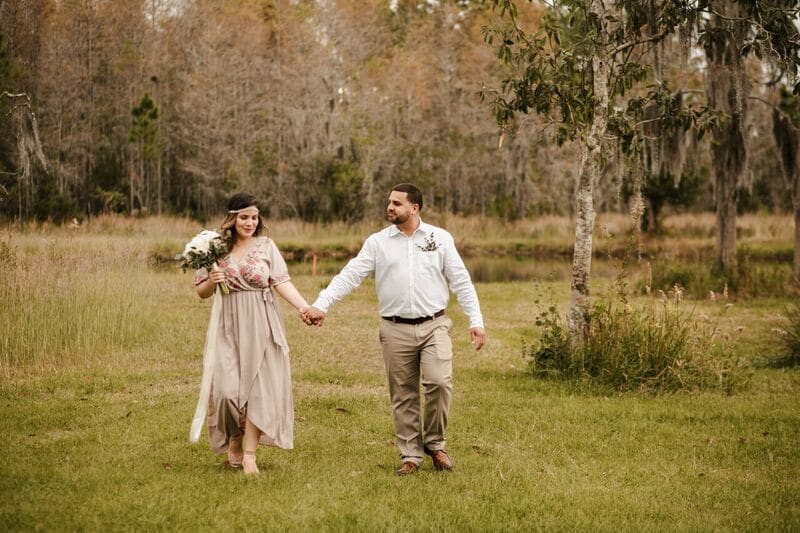 For the Love of Events - casual engaged couple walks through field backed by woods