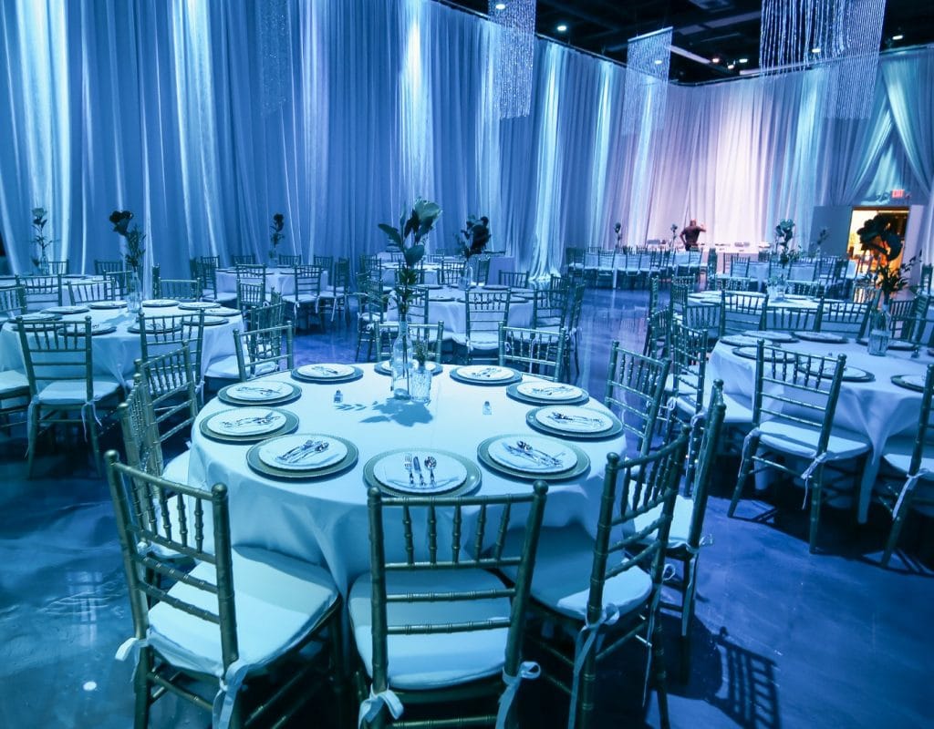Live-Love-Laugh-Events-Ten seat round table with simple centerpieces in dark blue/purple lit reception hall