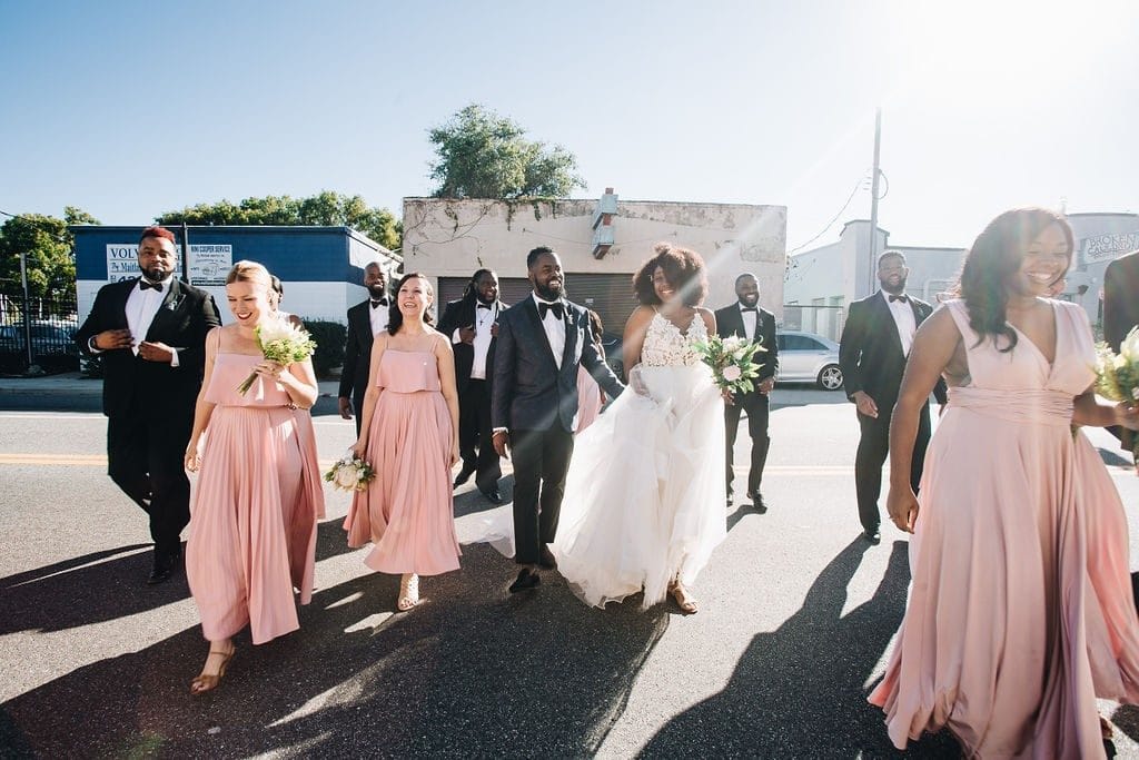 Live-Love-Laugh-Events-Bride, Groom and wedding party walking in the road with sunshine and blue skies