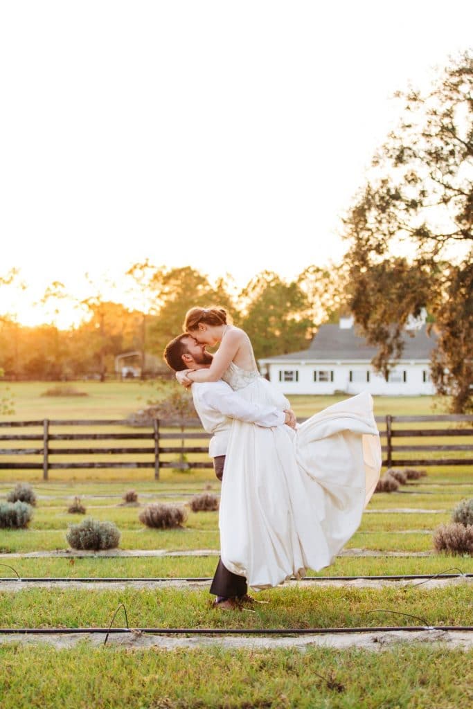 Live-Love-Laugh-Events-Groom holding bride in the air at sunset while kissing