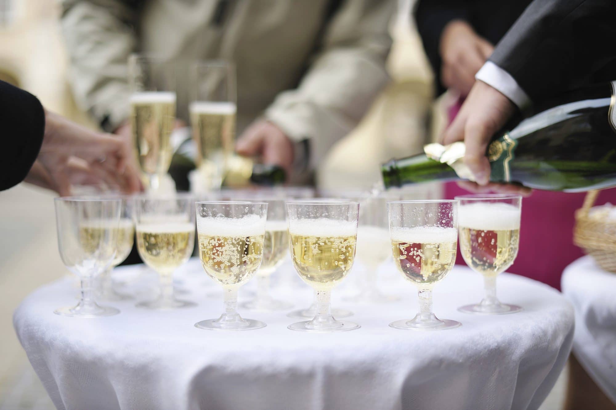 ABC Fine Wine - Glasses of champagne with blurred people standing around the table