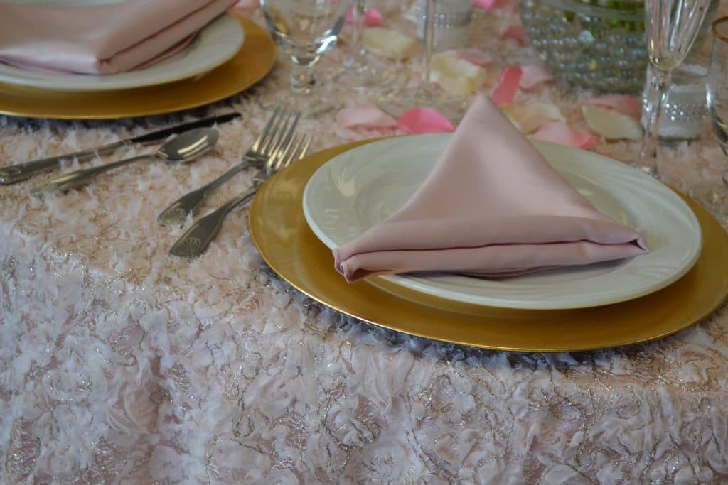 Connie-Duglin-Linen-Soft pink and silver linen with gold chargers, white dinner plates and soft pink napkin.
