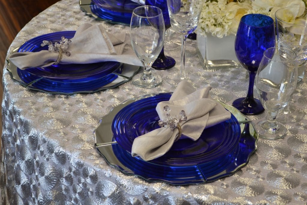 Connie-Duglin-Linen-Silver coin pattern linen with silver reflective charger and royal blue glass plate and wine glass