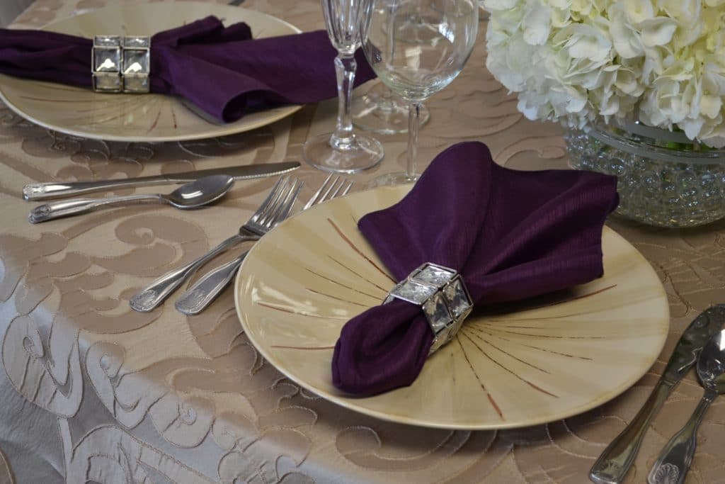 Connie-Duglin-Linen-Victorian style damask pattern linen with creme dinner plates and royal purple napkins