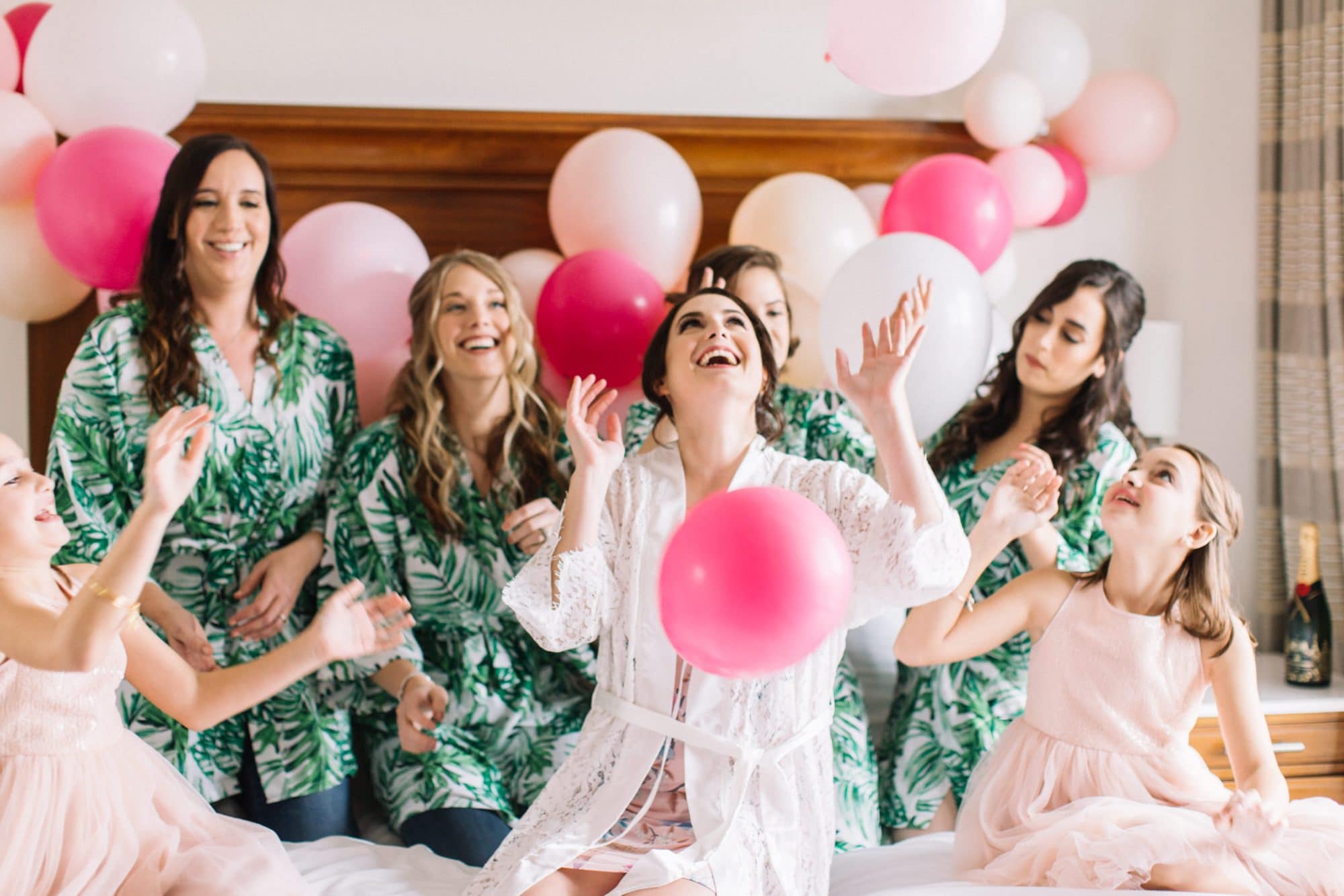 Pearl White Events - bride and bridesmaids sitting on bed surrounded by balloons