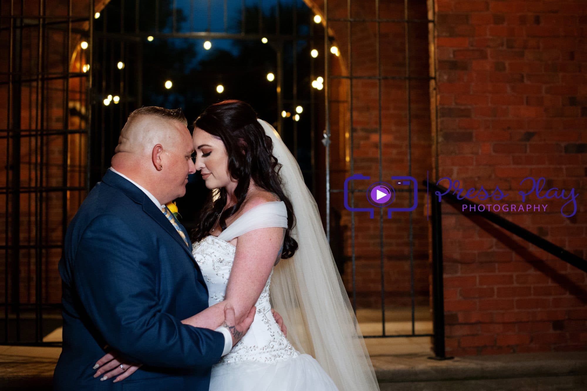 Bride and groom in brick archway with market lighting