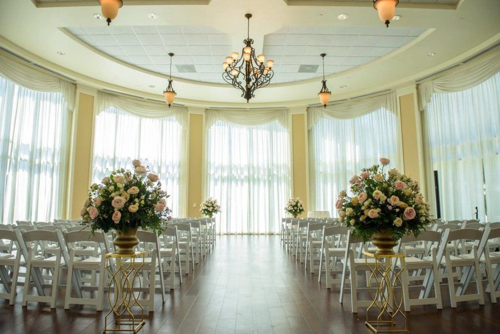 As-You-Wish- Grand windows in arched room set for ceremony with white floral arrangements