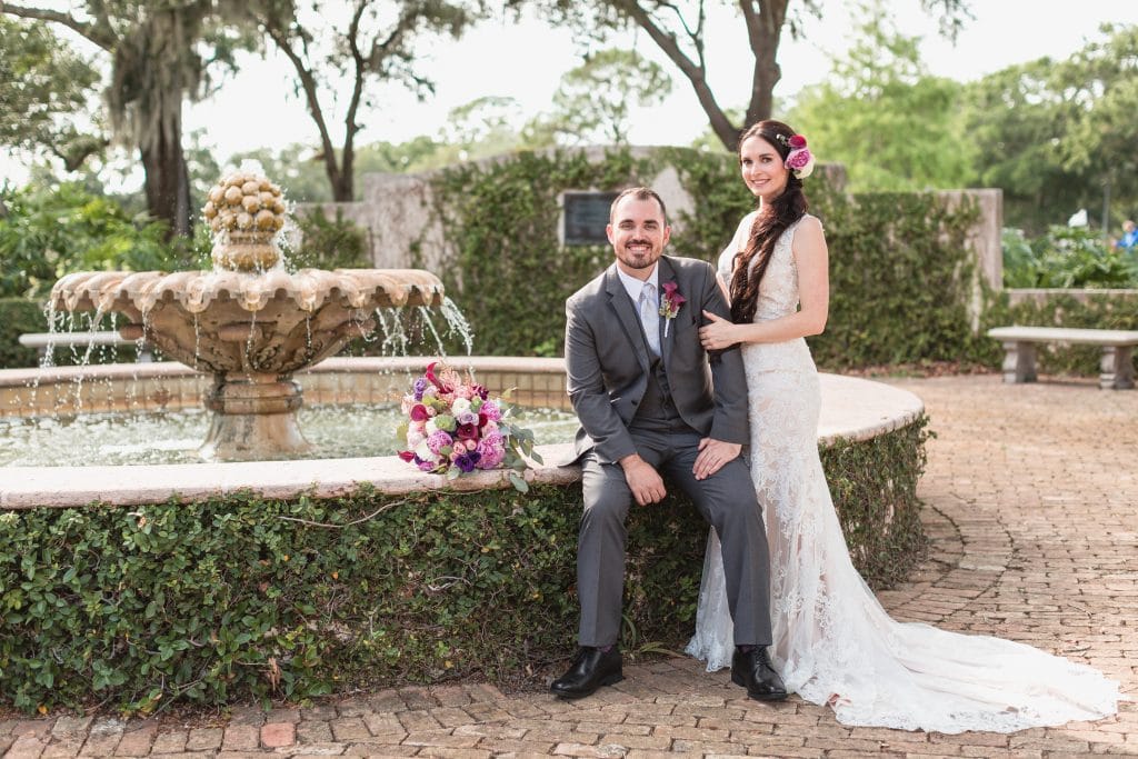 bride and groom at fountain with pink flowers
