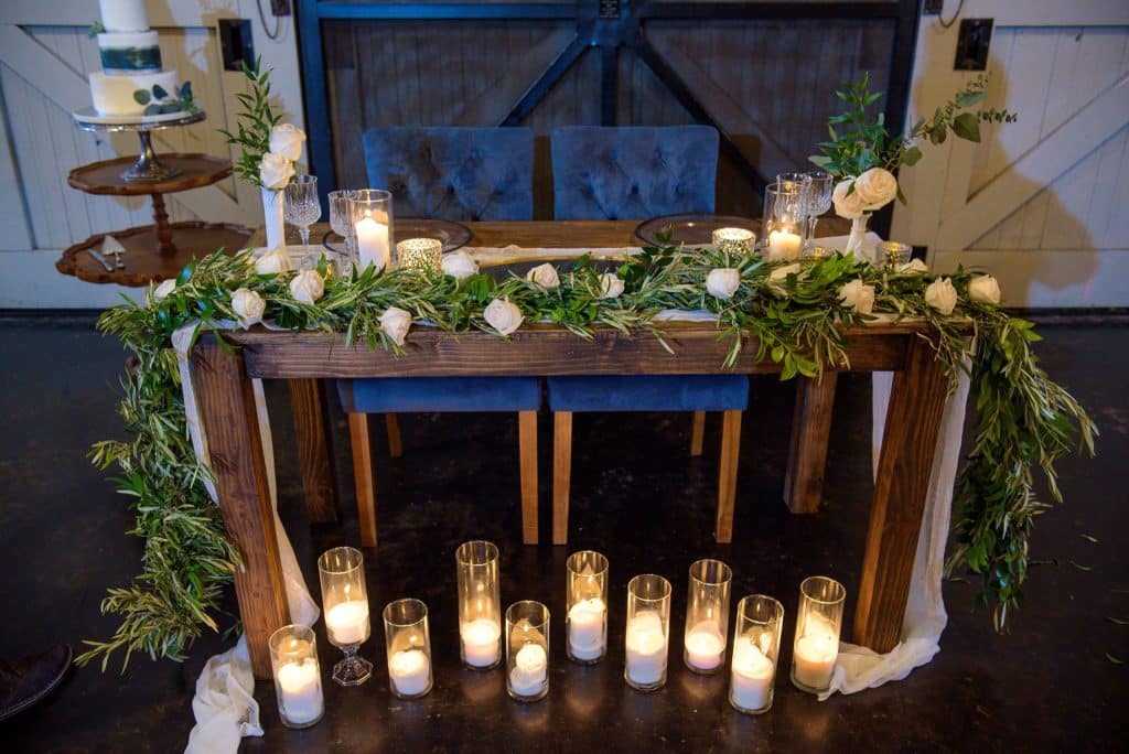 sweetheart table with blue chairs and greenery