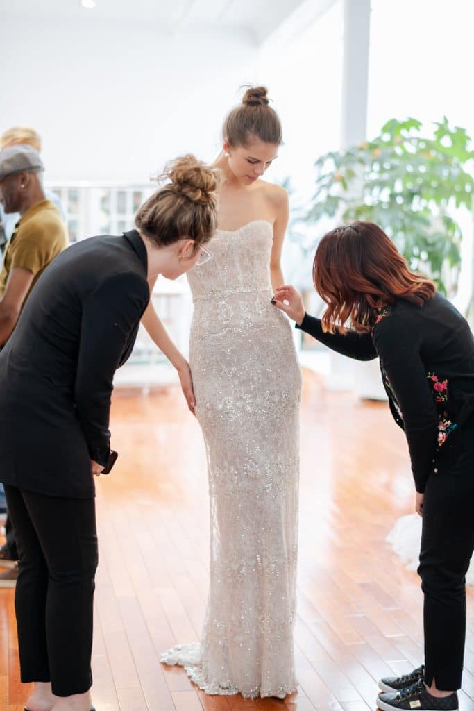 Solutions Bridal - wedding planners making adjustments to slim bridal gown