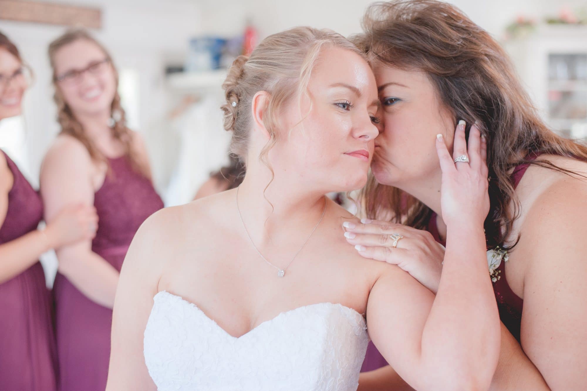 Bride Brittany receiving kiss on cheek from her mom.