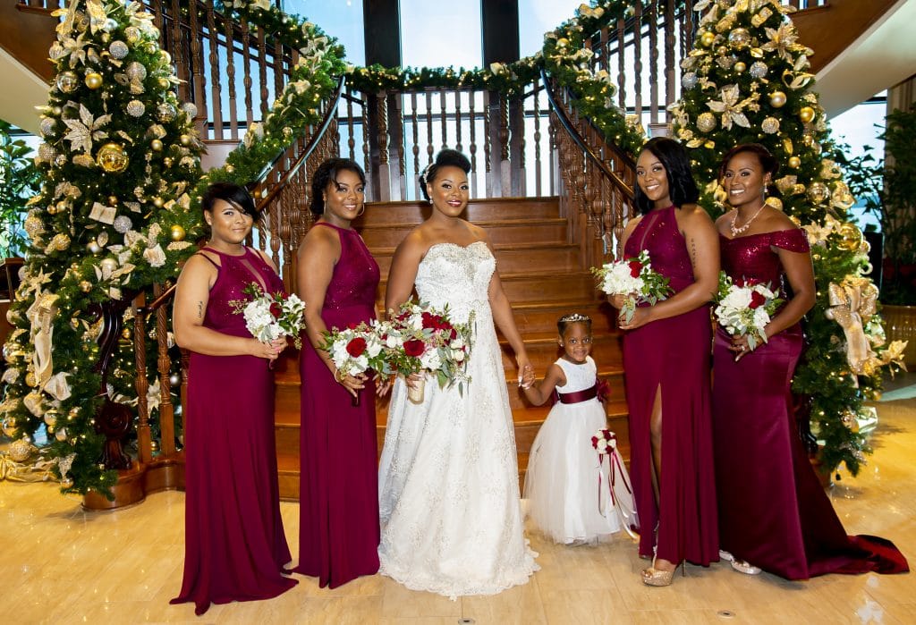 Shaneika with bridesmaids and flower girl in front of sweeping staircase