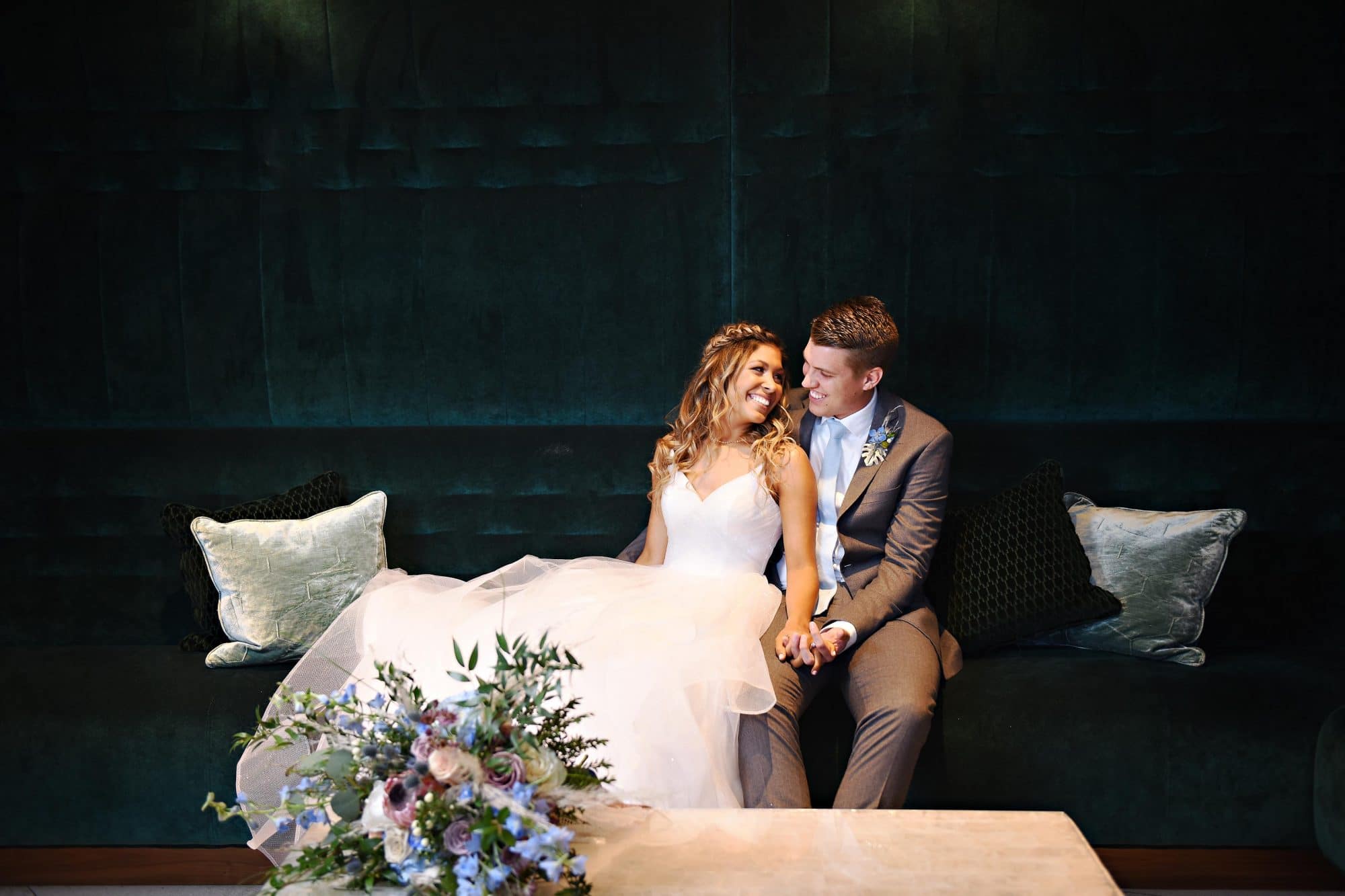 bride and groom on dark couch and dark wall