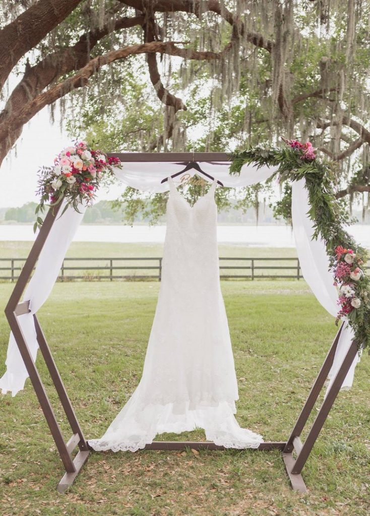 Perfect-Day-Productions- Bride's dress hung up on octagonal shaped structure outside under a tree