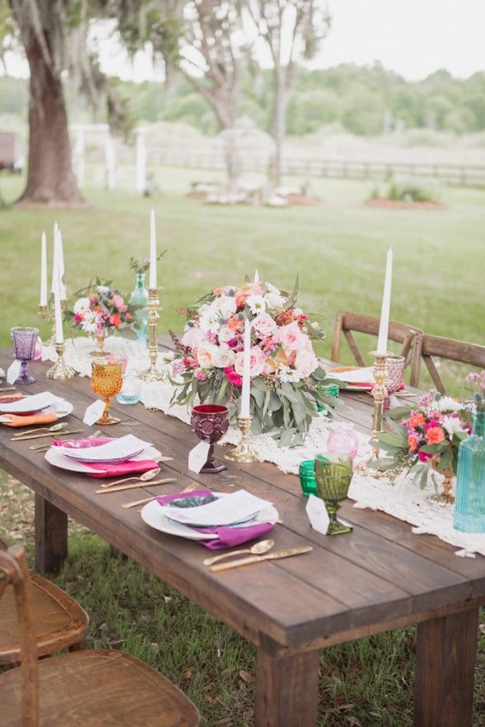 Perfect-Day-Productions-Outdoor table setting on a wooden bench with multicolor floral centerpieces