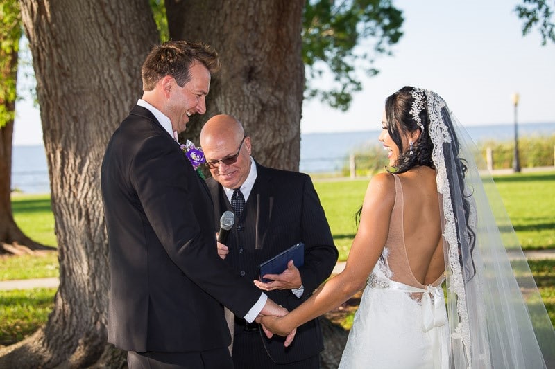 Pastor-Mike-Weddings-Groom putting ring on bride's hand during outdoor ceremony