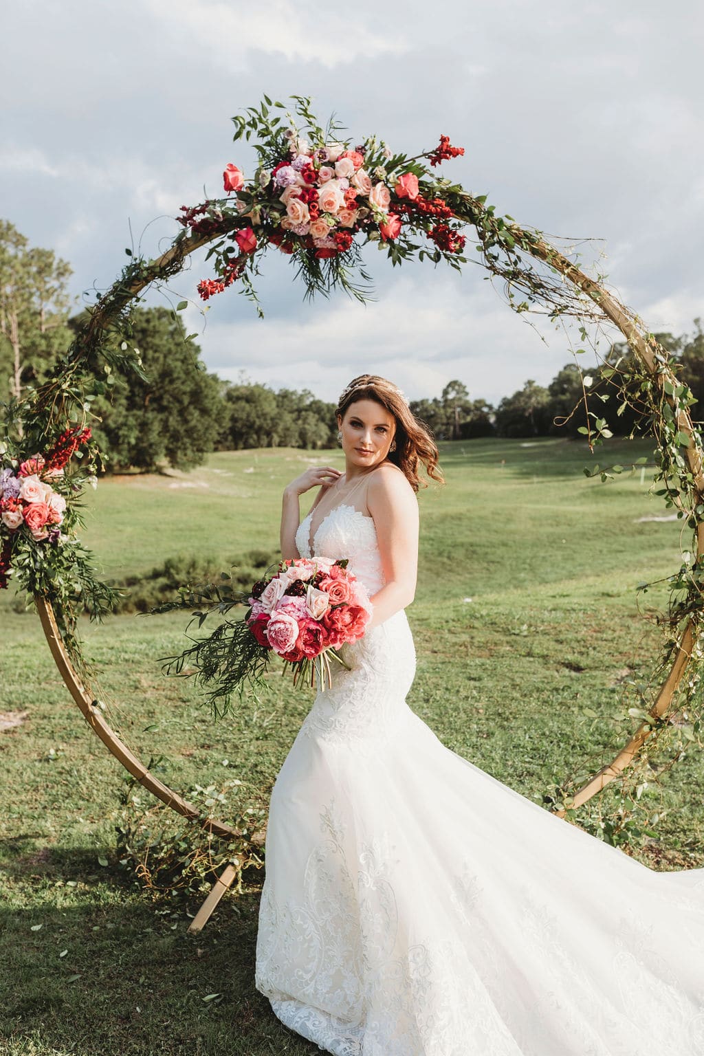 bride standing in front of a ring with flowers outside
