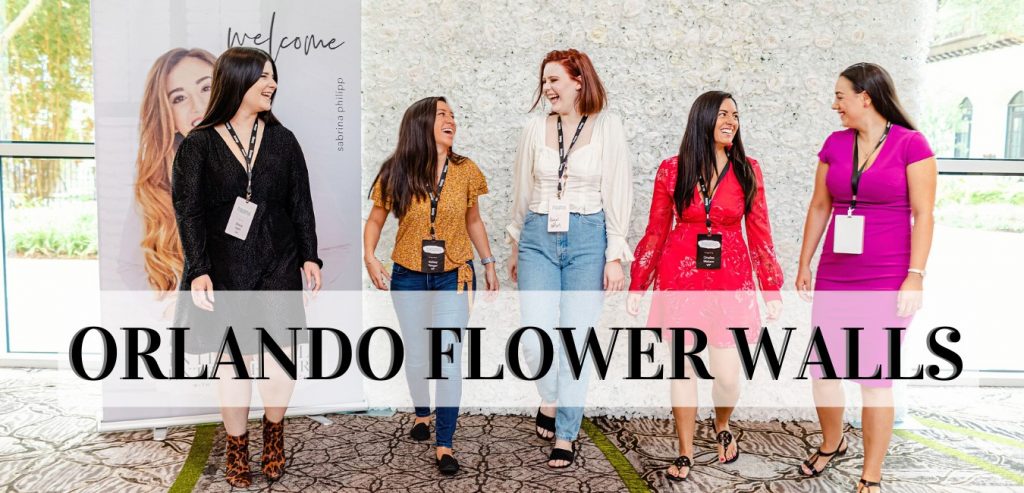 Orlando-Flower-Walls-Five ladies laughing in front of a white flower wall with logo