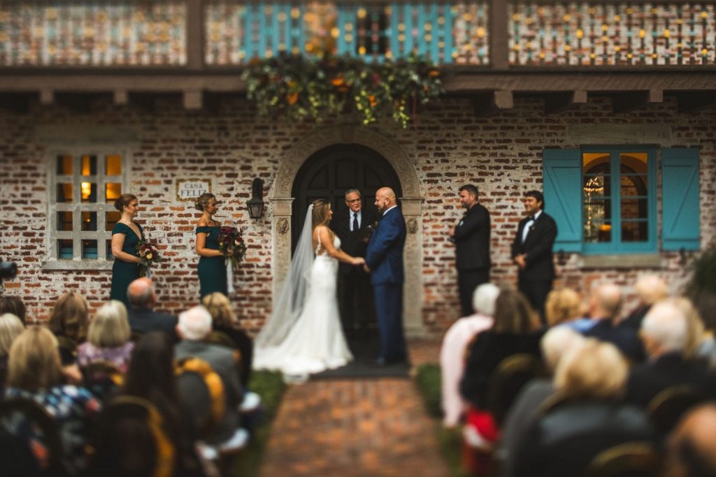 Bride & Groom during ceremony against brick wall and turquoise window shutters